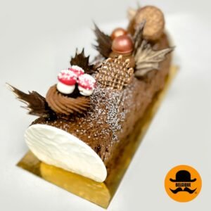 Traditional chocolate Christmas log decorated with festive accents, from Belgique Patisserie.”